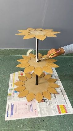 a person is making a paper sunflower sculpture