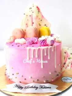 a pink birthday cake with white icing and sprinkles on the top