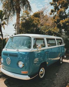 an old vw bus is parked on the side of the road in front of some palm trees