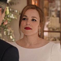 a woman in a white dress looking into the distance with a man standing next to her