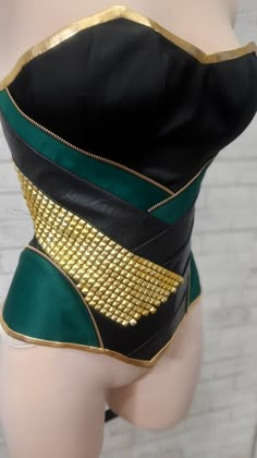 a woman's green and black corset with gold zippers on it
