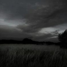 the sky is dark and cloudy as it sits over a field