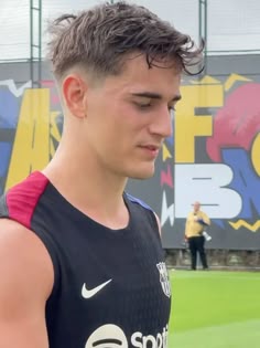 a young man standing on top of a soccer field wearing a black and red shirt