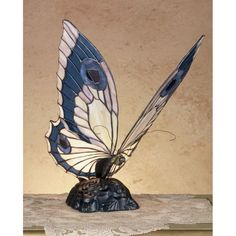 a blue and white butterfly figurine sitting on top of a wooden table next to a wall