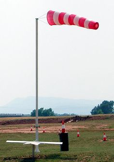 a red and white flag is in the middle of a field with orange cones around it