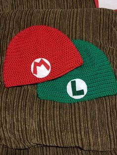 two knitted hats sitting on top of a brown couch next to eachother