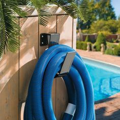 a blue hose attached to the side of a wooden fence next to a swimming pool