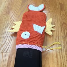 a crocheted cell phone case sitting on top of a wooden floor