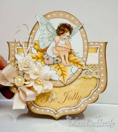 a hand holding a card with an image of a fairy sitting on top of it