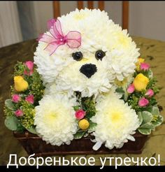 a teddy bear made out of flowers sitting in a basket on top of a table
