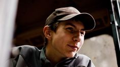 a young man wearing a baseball cap looking off into the distance