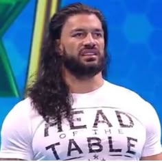a man with long hair wearing a t - shirt that says head of the table