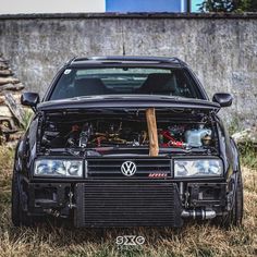 an old car with the hood up and its engine in it's trunk is parked on some dry grass