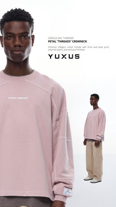 a man standing in front of a white background wearing a pink sweatshirt and khaki pants