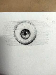 a pencil drawing of an eyeball in the middle of a piece of white paper