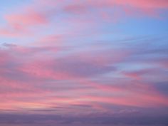 the sky is pink and blue as it sets on an overcast day at the beach