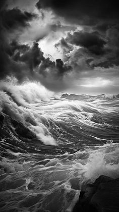 black and white photo of ocean waves with dark clouds