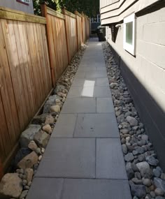 there is a long walkway with rocks on the side and in between it, next to a fence