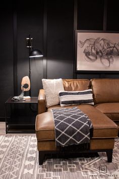 a brown leather couch sitting next to a black table with a lamp on top of it
