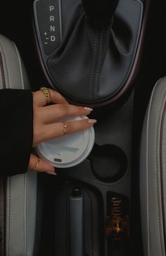 a woman's hand on a plate in the center console of a car with other accessories