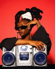 a woman with dreadlocks sitting in front of a boombox