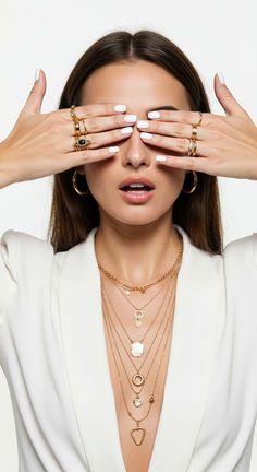 a woman holding her hands over her eyes with gold jewelry on top of her head