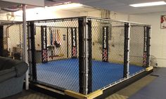 the inside of a caged in gym with blue flooring and black metal bars