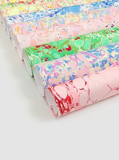 four different colored papers are stacked on top of each other, one is pink and the other is green