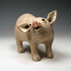 a small ceramic pig figurine on a white surface with one eye open and the other half closed