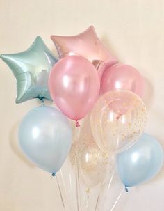 a vase filled with balloons and stars on top of a white table next to a wall