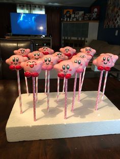 there are many pink candies with faces on them and sticks sticking out of them