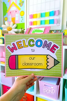 a person holding up a sign that says welcome to our classroom with crayons in the background