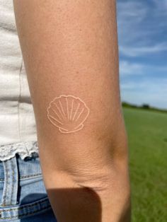 a woman's arm with a shell tattoo on the left side of her arm