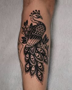 a black and white peacock tattoo on the leg