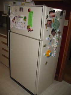 a white refrigerator with magnets and pictures on the door is shown in this kitchen