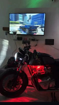 a motorcycle is parked in front of a flat screen tv on a wall with red lights