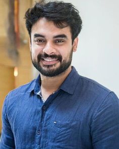 a man in a blue shirt smiling at the camera