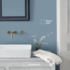 a bathroom sink sitting under a mirror next to a wall mounted faucet and towel dispenser