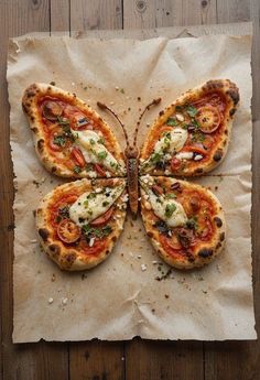 a butterfly shaped pizza sitting on top of a piece of parchment paper with cheese and toppings
