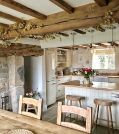 a kitchen with wooden tables and stools next to a stone fireplace in the center