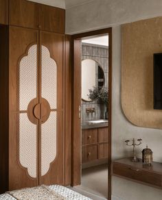 a bedroom with a bed, mirror and television on the wall next to wooden cabinets