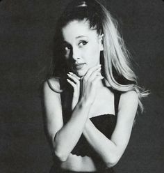 a black and white photo of a woman with her hands on her chest, looking at the camera