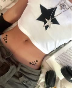 a woman laying on top of a bed with her stomach covered in stars and an open book