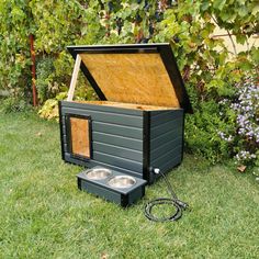 an outdoor dog house with two dogs in it and a water bowl on the ground