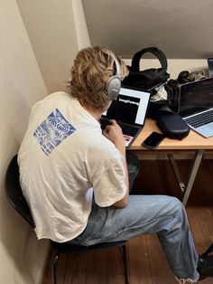 a man sitting at a desk with two laptops and headphones on his ears