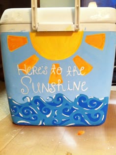 a cooler with the words here's to be sunshine painted on it, sitting on a counter