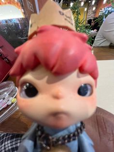 a doll with red hair and a crown on it's head sitting on a table