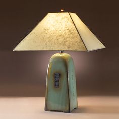 a table lamp with a green ceramic base and a white shade on the top,