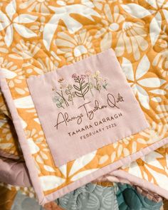 a close up of a quilt with a name tag on the front and back of it