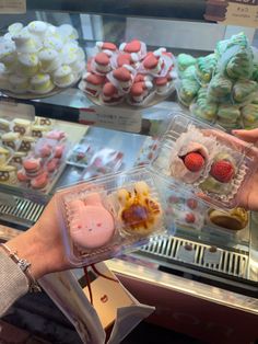 a person holding up a plastic container filled with desserts